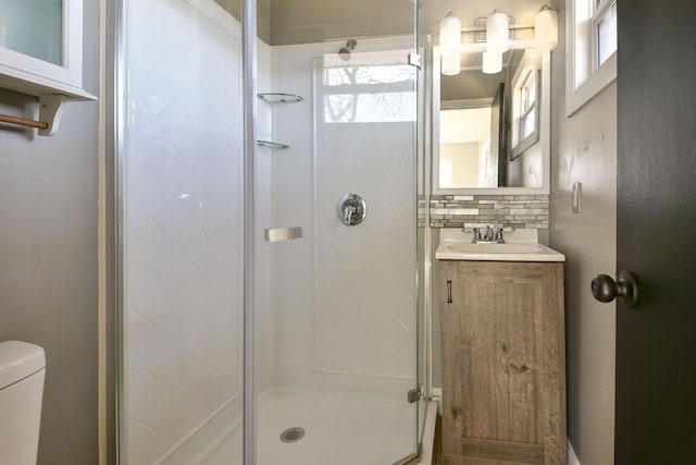 full bath with vanity, a shower stall, toilet, and backsplash