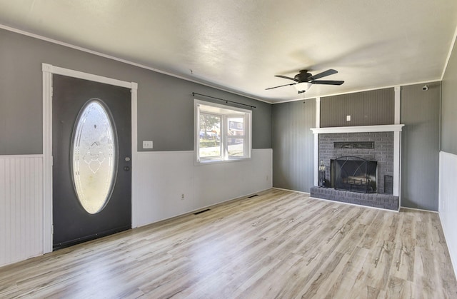 entryway featuring visible vents, a wainscoted wall, a brick fireplace, and wood finished floors