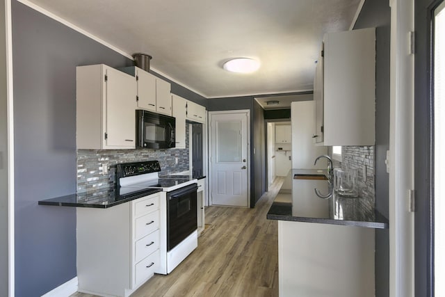 kitchen with a sink, dark countertops, black microwave, and range with electric stovetop