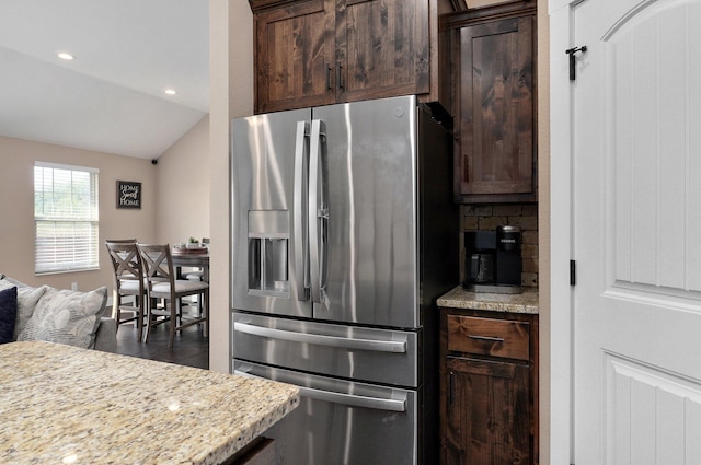 kitchen featuring stainless steel refrigerator with ice dispenser, backsplash, recessed lighting, light stone countertops, and dark brown cabinets