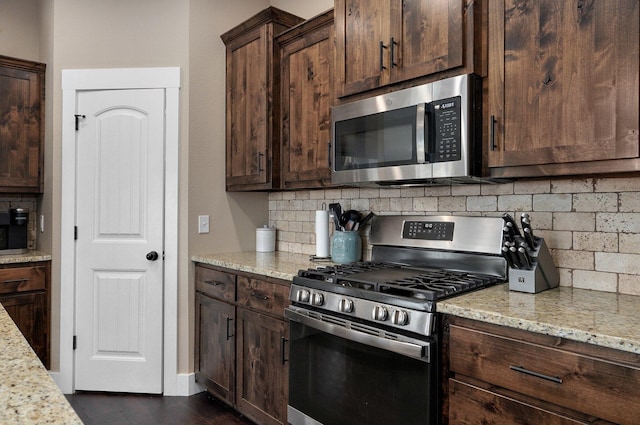 kitchen with light stone counters, dark brown cabinetry, backsplash, and stainless steel appliances