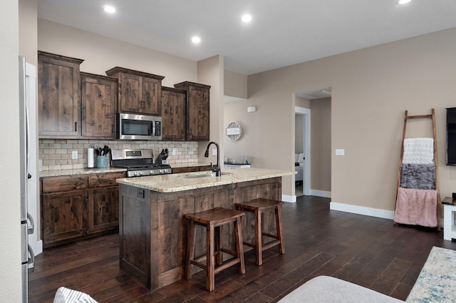 kitchen with a sink, stainless steel appliances, backsplash, and dark wood-style flooring