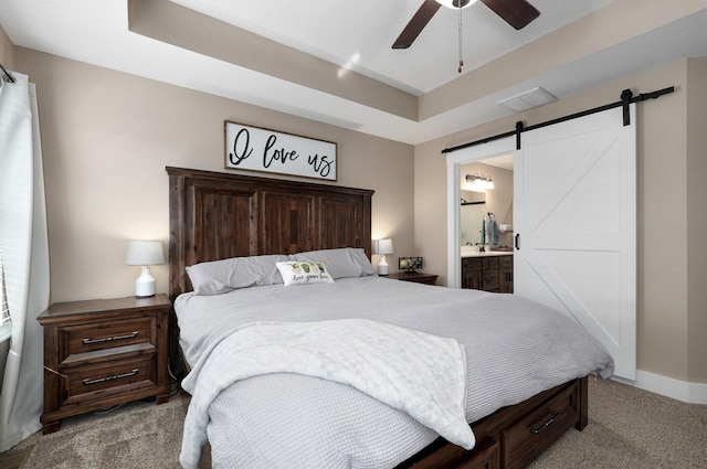 bedroom featuring visible vents, connected bathroom, a barn door, carpet floors, and a raised ceiling