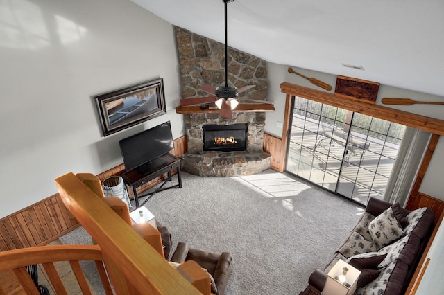 living room featuring visible vents, wooden walls, a fireplace, carpet flooring, and vaulted ceiling