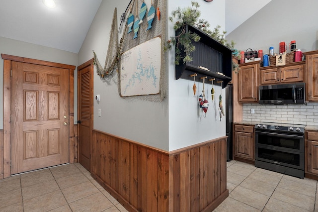 kitchen with light countertops, wooden walls, double oven range, and a wainscoted wall