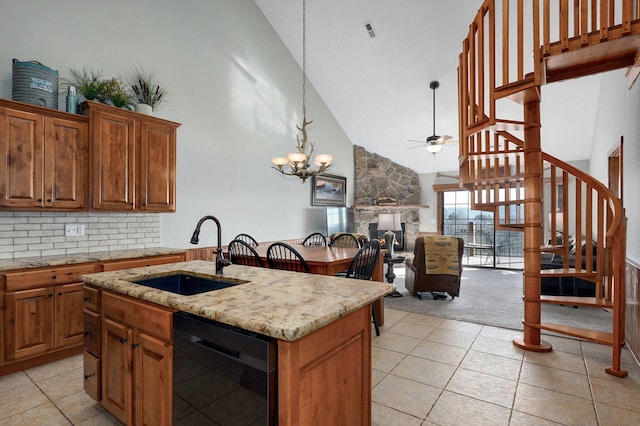 kitchen with a kitchen island with sink, a sink, a stone fireplace, dishwasher, and open floor plan