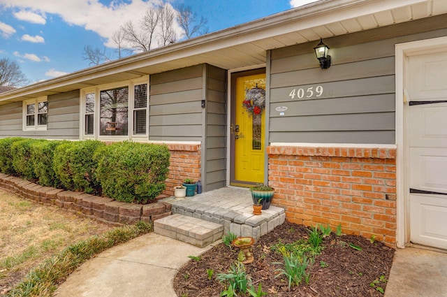 view of exterior entry with a garage and brick siding