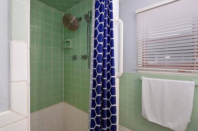 bathroom with a shower stall, tile walls, and a wainscoted wall