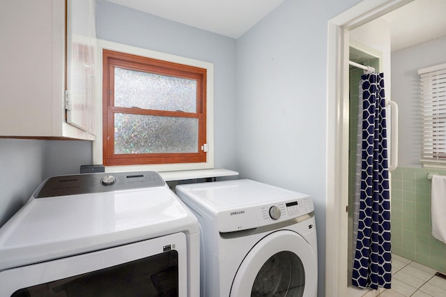 laundry room with light tile patterned floors, cabinet space, tile walls, and washing machine and clothes dryer