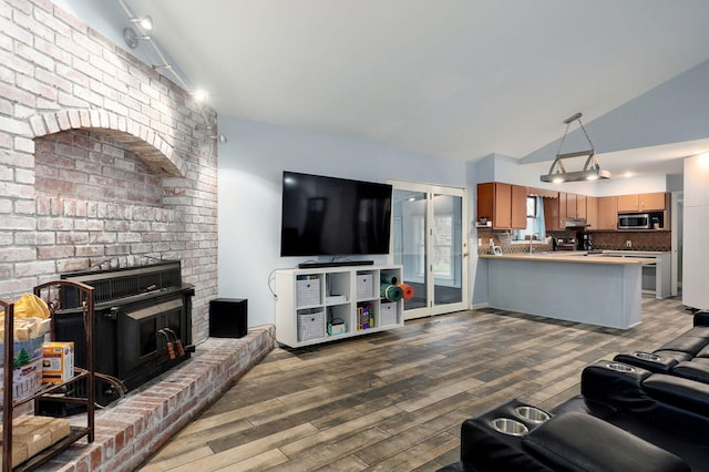 living area featuring a brick fireplace, wood finished floors, and vaulted ceiling