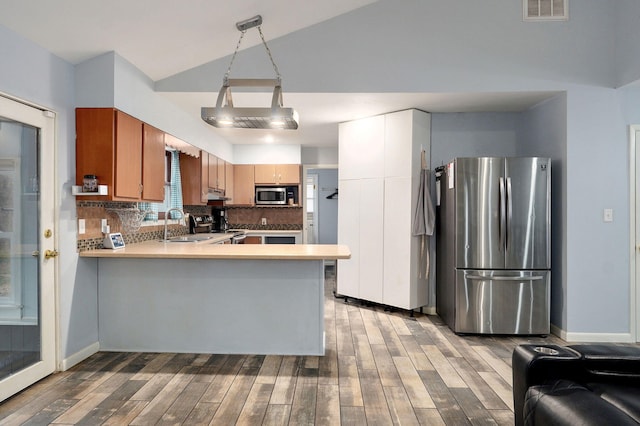 kitchen featuring visible vents, backsplash, wood finished floors, appliances with stainless steel finishes, and a peninsula