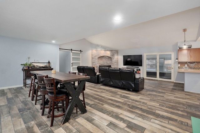 dining room featuring baseboards, a barn door, vaulted ceiling, recessed lighting, and wood finished floors