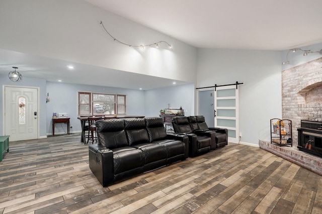 living area with a barn door, baseboards, high vaulted ceiling, and wood finished floors