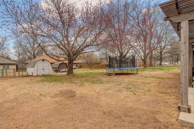 view of yard with an outbuilding, a trampoline, fence, and a storage unit