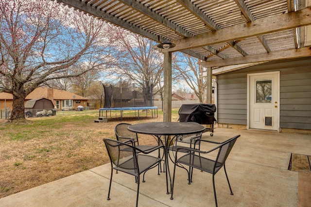 view of patio featuring a trampoline, fence, outdoor dining space, a pergola, and area for grilling