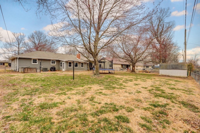 view of yard featuring central AC unit, fence, a hot tub, an outdoor structure, and a trampoline