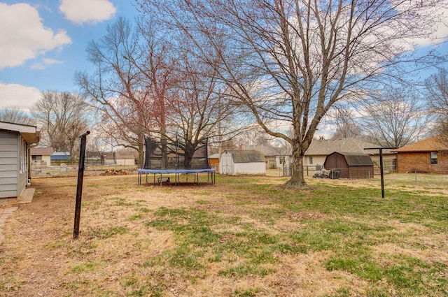 view of yard with a storage unit, a trampoline, an outdoor structure, and fence