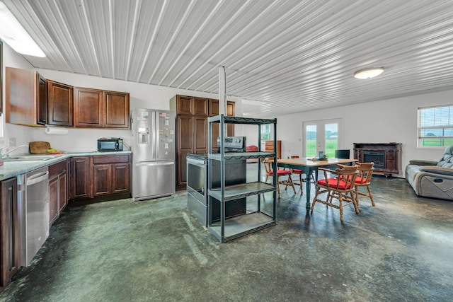 kitchen featuring finished concrete flooring, a sink, stainless steel appliances, light countertops, and open floor plan