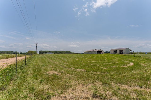view of yard featuring a rural view, an outdoor structure, and a pole building