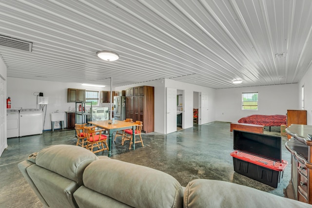 living area with visible vents, washer and dryer, and concrete flooring