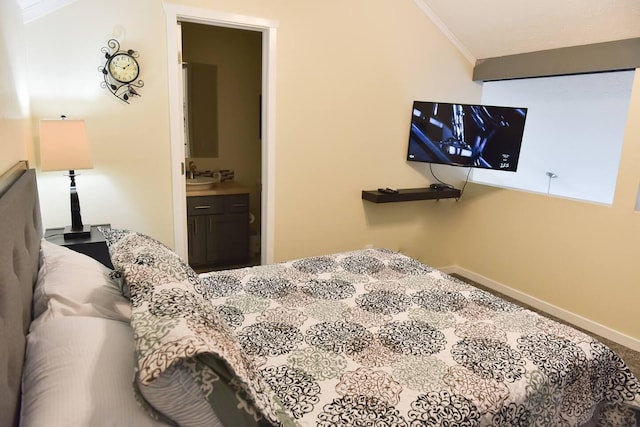 bedroom featuring baseboards, vaulted ceiling, ornamental molding, ensuite bathroom, and a sink