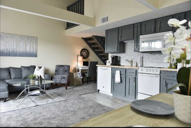 kitchen with visible vents, open floor plan, light countertops, decorative backsplash, and white appliances