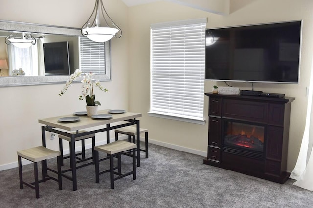 carpeted dining area featuring a glass covered fireplace and baseboards