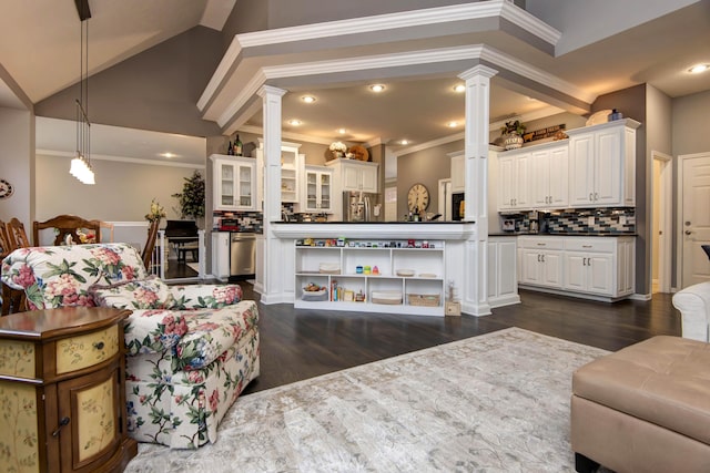 living area featuring ornate columns, dark wood finished floors, recessed lighting, ornamental molding, and vaulted ceiling