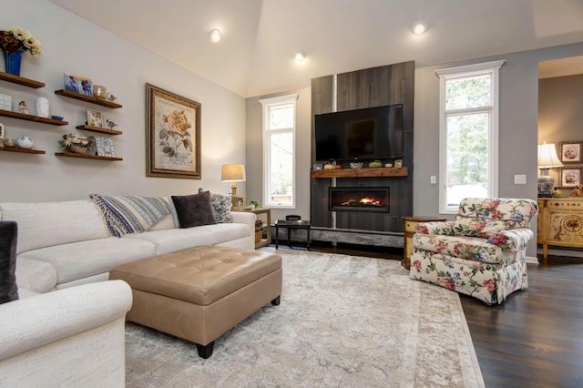 living area with dark wood-style floors, a fireplace, and vaulted ceiling