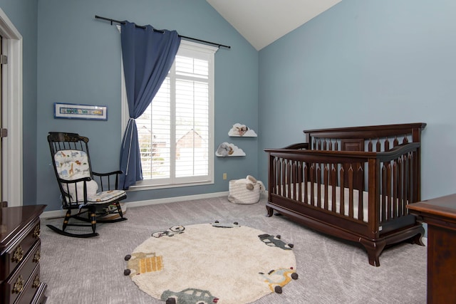 carpeted bedroom with vaulted ceiling, a nursery area, and baseboards