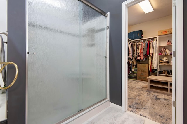 bathroom with a spacious closet and a stall shower