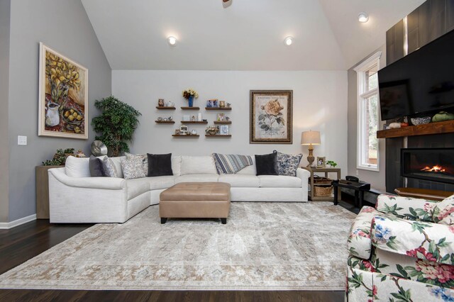 living area featuring vaulted ceiling, wood finished floors, baseboards, and a large fireplace