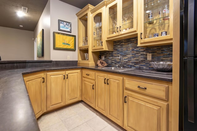 kitchen with dark countertops, tasteful backsplash, freestanding refrigerator, and a sink