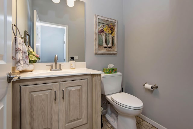 half bathroom featuring tile patterned floors, baseboards, toilet, and vanity