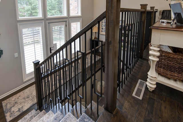 stairway featuring a high ceiling, wood finished floors, visible vents, and baseboards