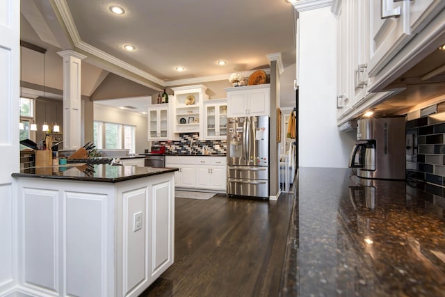 kitchen with decorative columns, dark wood-style flooring, stainless steel appliances, decorative backsplash, and white cabinetry