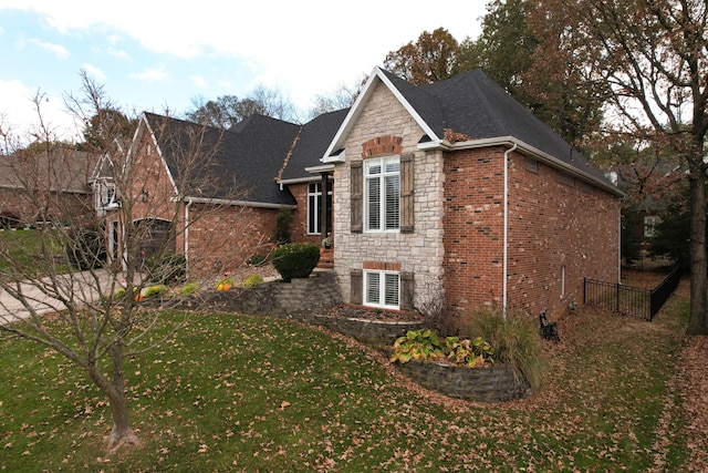 view of home's exterior featuring brick siding, stone siding, a shingled roof, and a yard