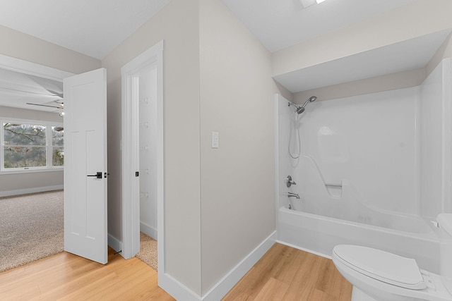 bathroom with toilet, bathtub / shower combination, wood finished floors, baseboards, and ceiling fan