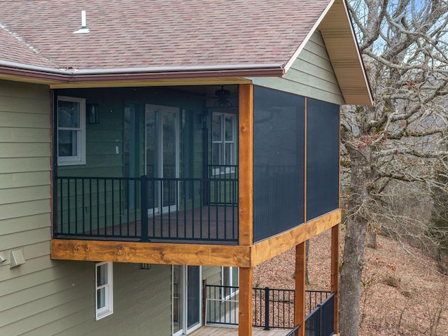 view of home's exterior featuring a sunroom and roof with shingles