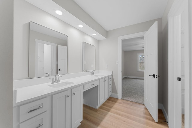 bathroom featuring double vanity, wood finished floors, baseboards, and a sink