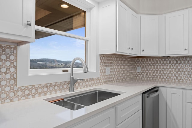 kitchen with white cabinetry, light countertops, backsplash, and a sink