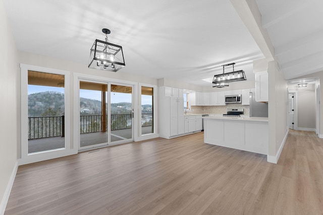 kitchen featuring backsplash, open floor plan, light countertops, appliances with stainless steel finishes, and white cabinetry