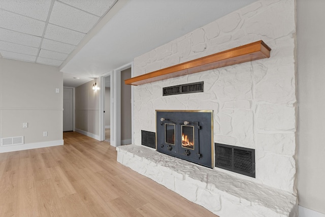 room details with visible vents, a stone fireplace, and wood finished floors