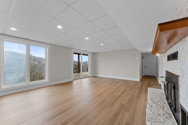 unfurnished living room with light wood-style flooring, recessed lighting, a fireplace, a paneled ceiling, and baseboards