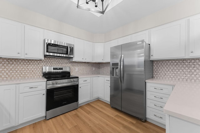 kitchen featuring light wood-style flooring, backsplash, stainless steel appliances, white cabinets, and light countertops