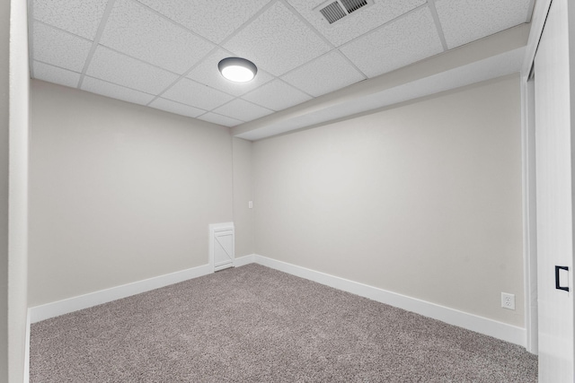 empty room with baseboards, visible vents, carpet floors, and a paneled ceiling