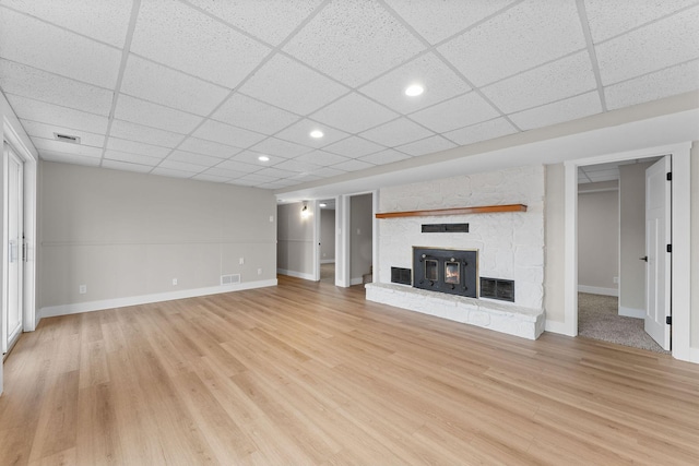 unfurnished living room with a fireplace, visible vents, light wood finished floors, and a paneled ceiling