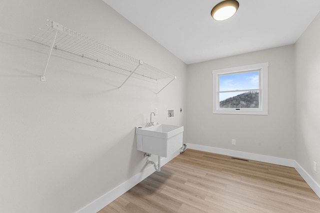 laundry room featuring light wood finished floors, laundry area, hookup for a washing machine, and baseboards