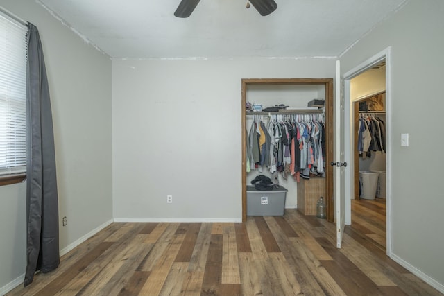 unfurnished bedroom with a ceiling fan, wood finished floors, a closet, and baseboards