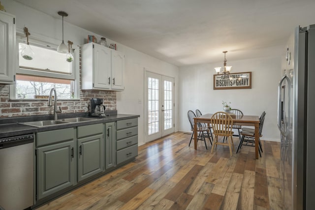 kitchen featuring dishwashing machine, freestanding refrigerator, a sink, french doors, and dark countertops